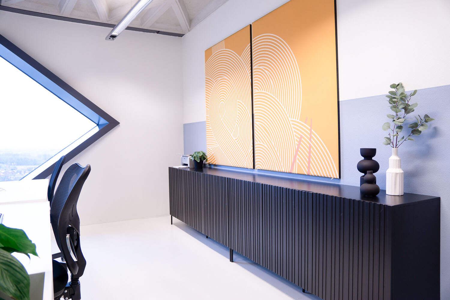 Muurdecoratie op akoestische print om de hinderlijke akoestiek te verbeteren bij de werkplekken.