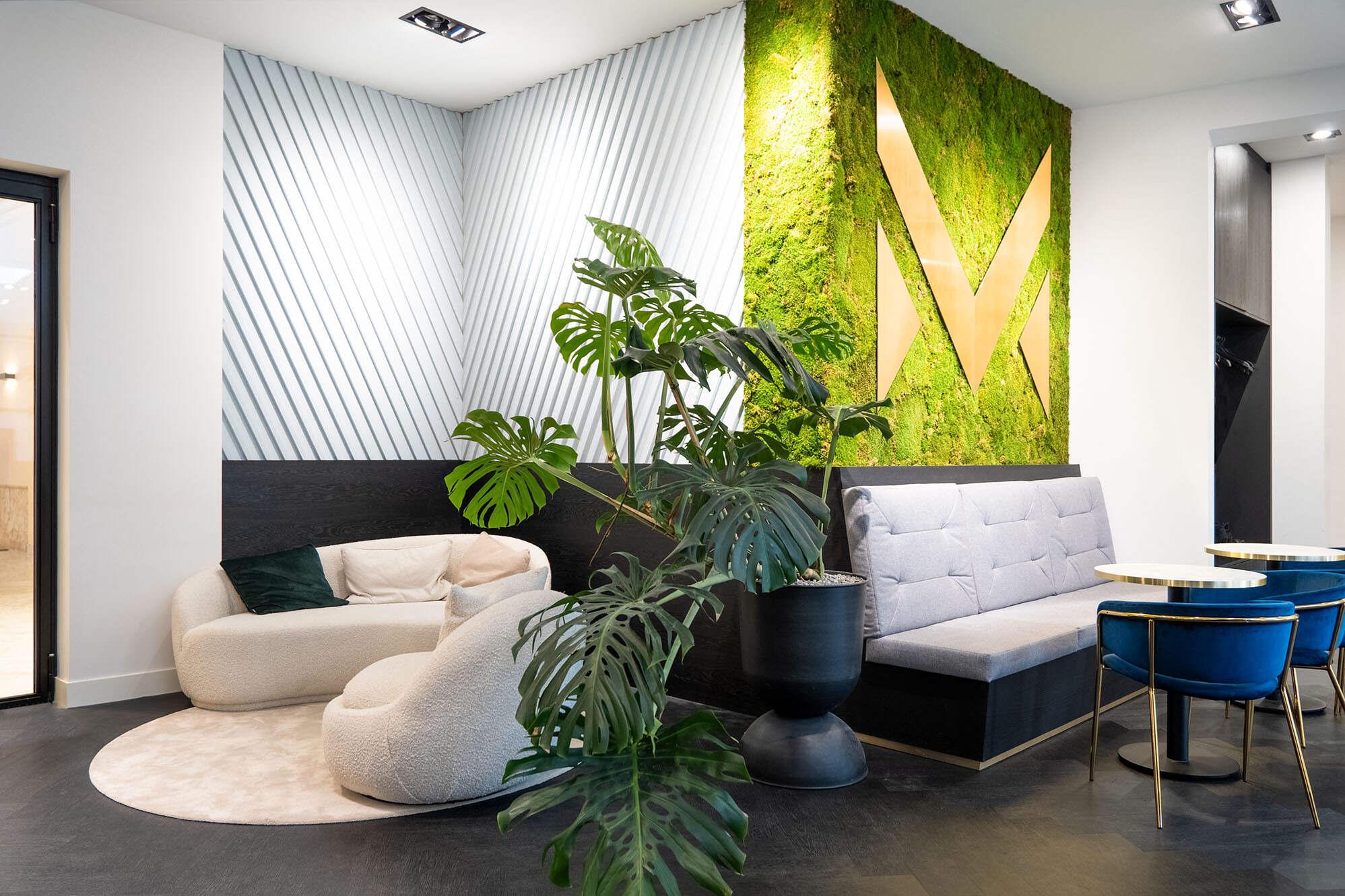 Verbouwing kantoorinrichting van een sfeervolle wachtruimte met grote planten.